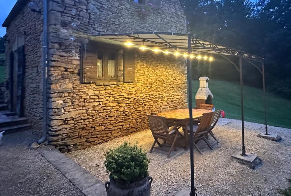 un patio avec une table et des chaises et un bâtiment dans l'établissement "Le Cantou" Authentique Périgourine avec belle Piscine au sel aux portes de Sarlat, à Proissans