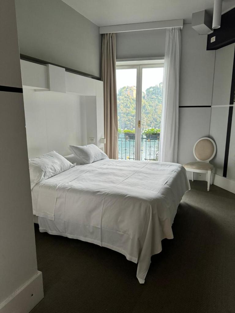 une chambre avec un lit blanc et une fenêtre dans l'établissement Portofino Deluxe Family Suite - balcony, sea view, private hotel beach, à Portofino