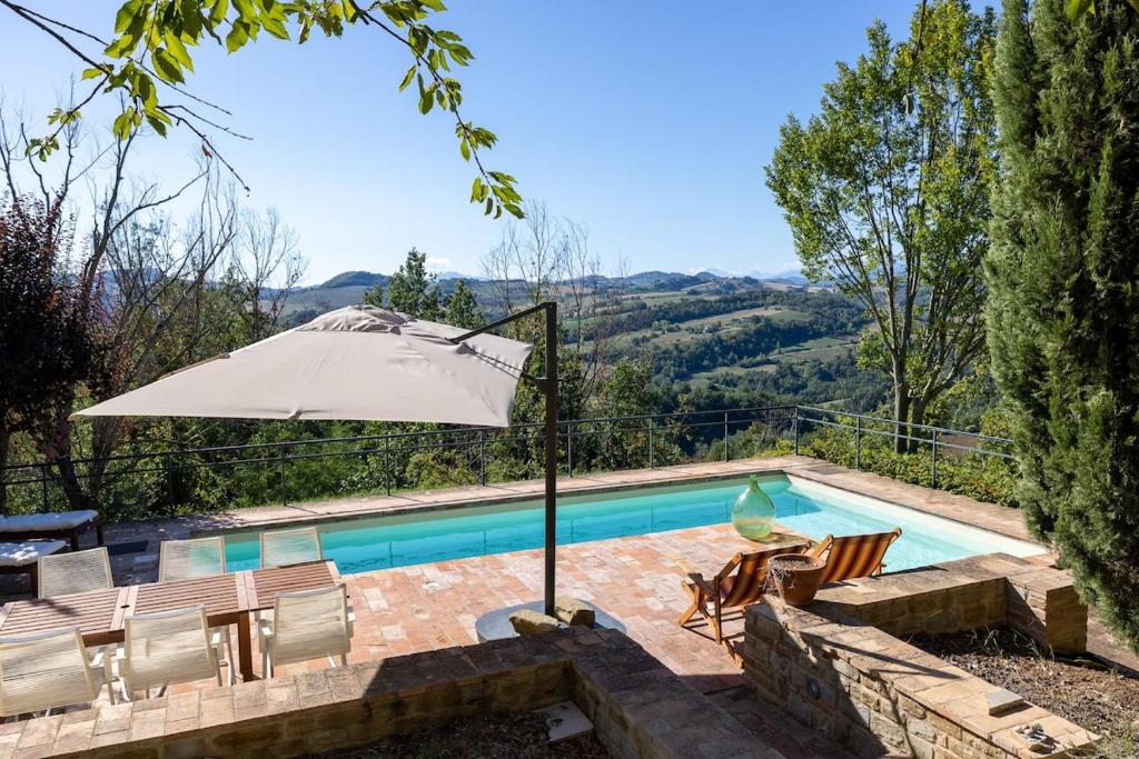 - une piscine avec un parasol et des chaises à côté de la piscine dans l'établissement Casa Santo Stefano, à San Girolamo di Sopra