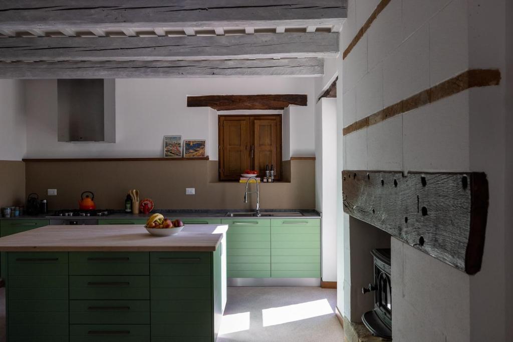 Il comprend une cuisine avec des placards verts et un plafond en bois. dans l'établissement Casa Santo Stefano, à San Girolamo di Sopra