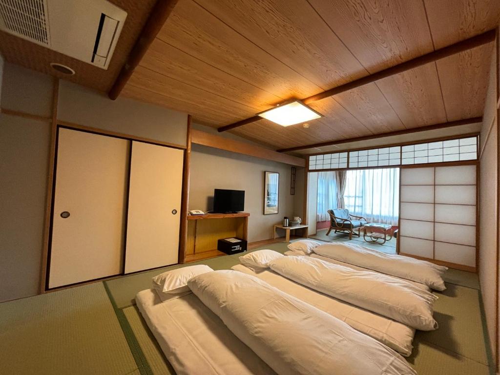 une rangée de 4 lits dans une chambre dans l'établissement Kameya Rakan, à Itō
