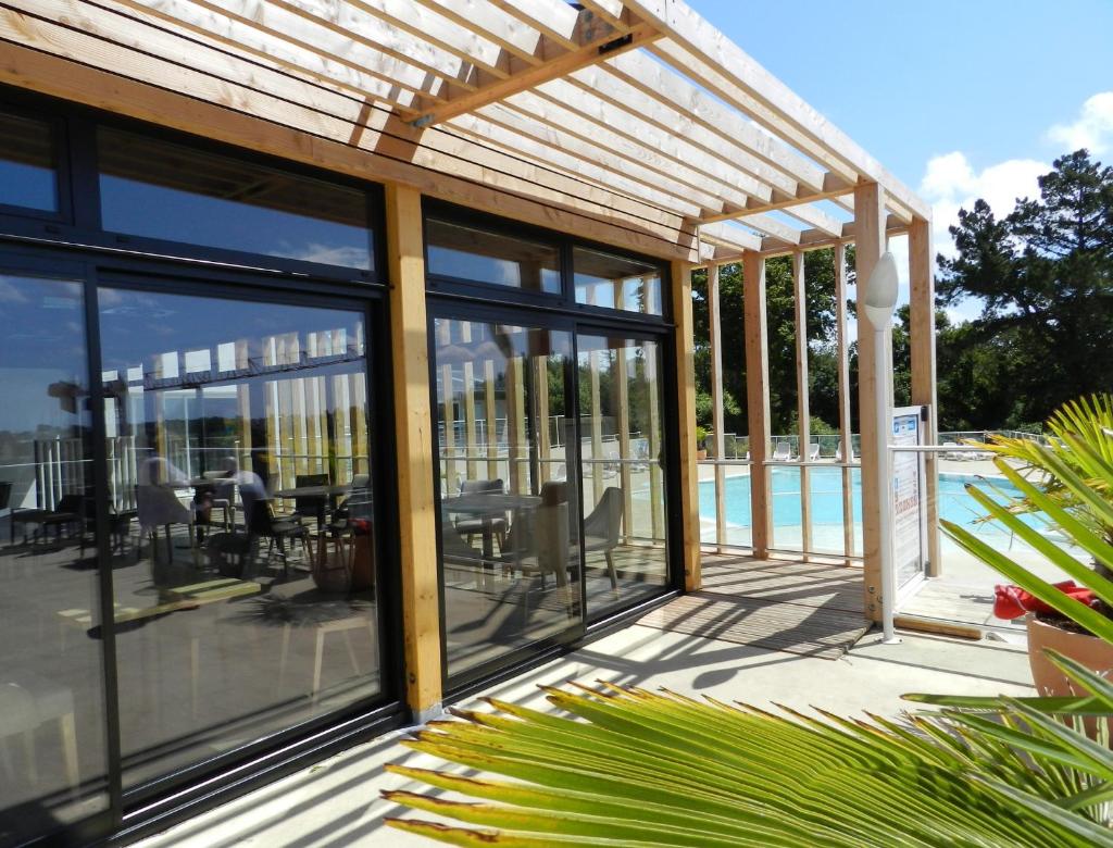 une maison avec des portes en verre et une piscine dans l'établissement Camping Les Sables Blancs, à Concarneau