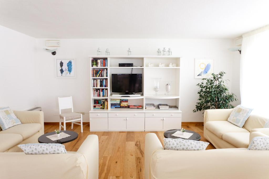 un salon avec des meubles blancs et une télévision à écran plat dans l'établissement HG Hotel Il Settebello, à Marina di Cecina