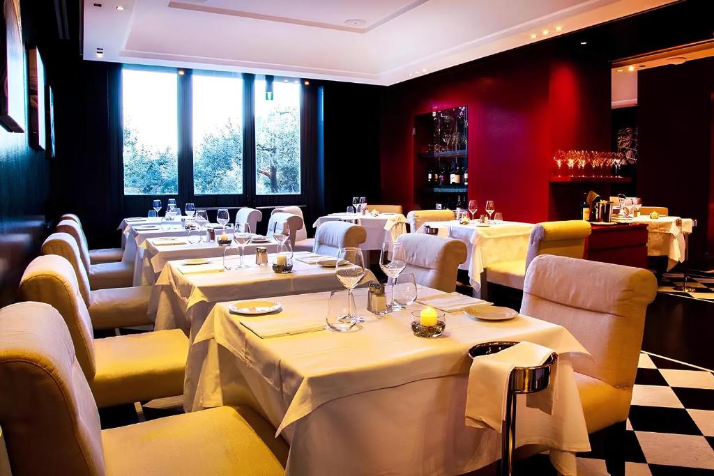 un restaurant avec des tables et des chaises blanches et des fenêtres dans l'établissement Portofino Deluxe Family Suite - balcony, sea view, private hotel beach, à Portofino