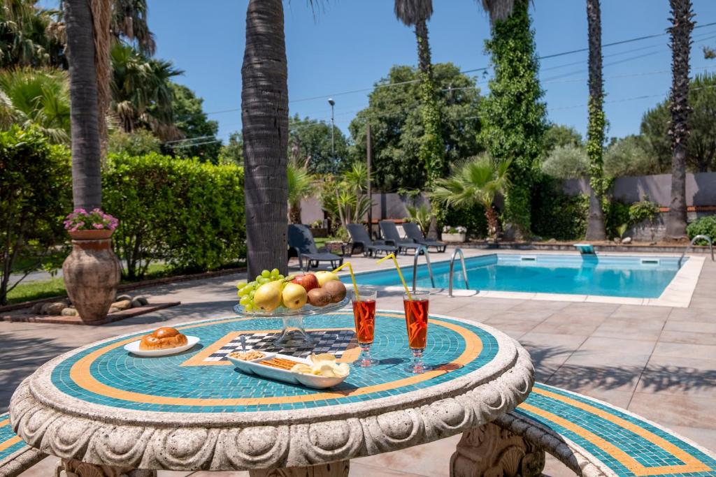 - une table avec des fruits et des boissons à côté de la piscine dans l'établissement Villa Etna da mare, à Fleri
