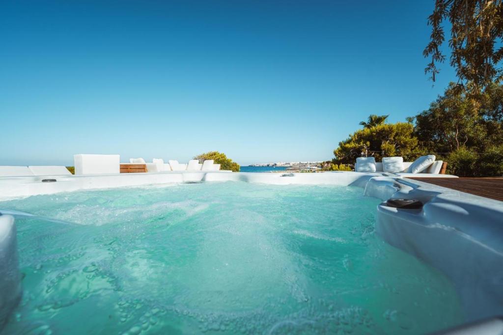 - une piscine avec de l'eau bleue et des chaises blanches dans l'établissement MareLuxe & Pool, à Polignano a Mare