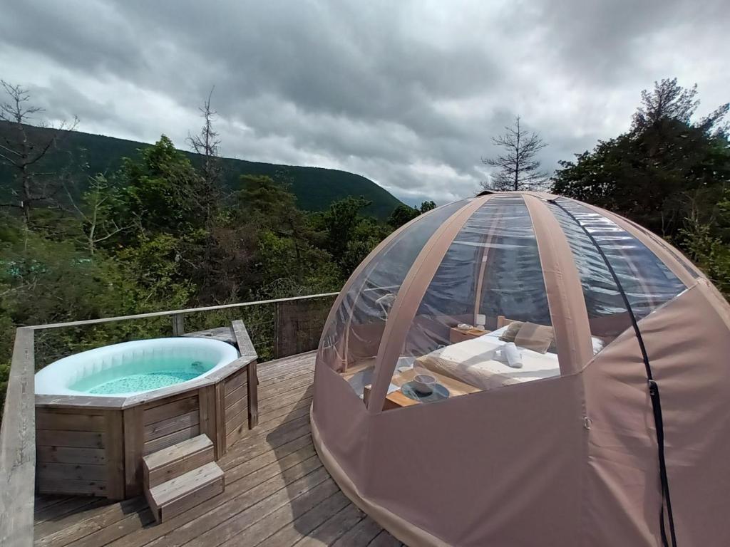 un bain à remous dans un iglooscrit sur une terrasse en bois dans l'établissement Bulle en bois sous les étoiles, à Champfromier