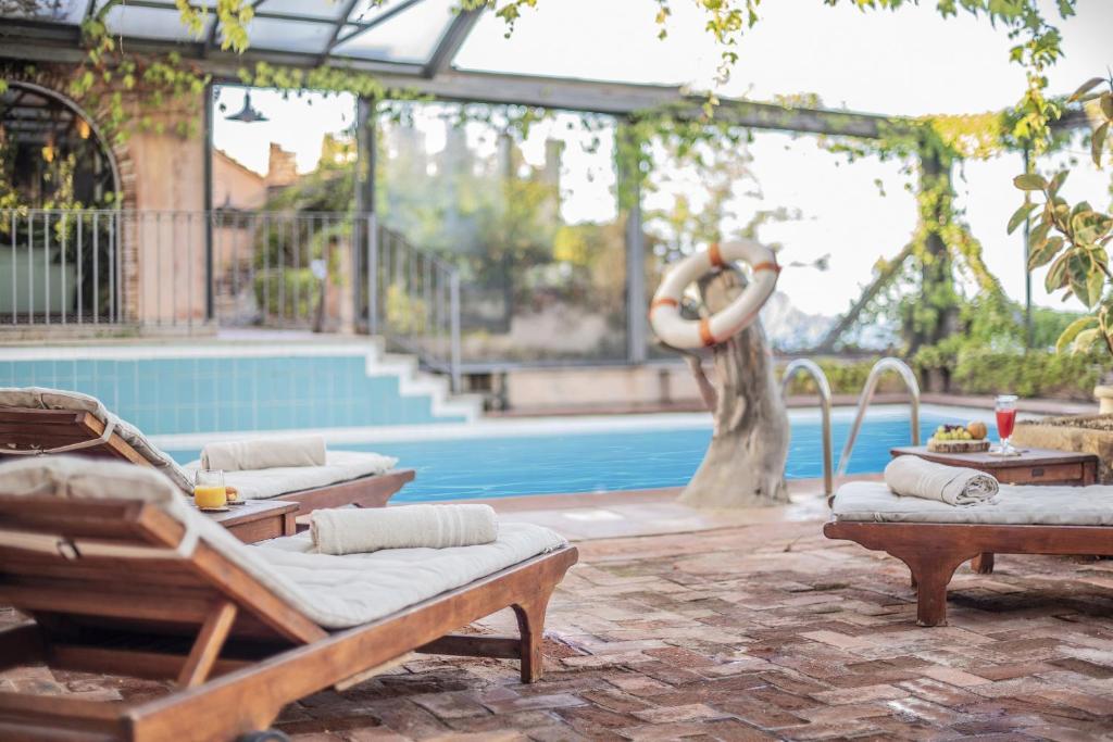 - une piscine avec 2 chaises longues et une femme debout à côté d'une piscine dans l'établissement Hotel Monte Turri - Adults Only, à Àrbatax