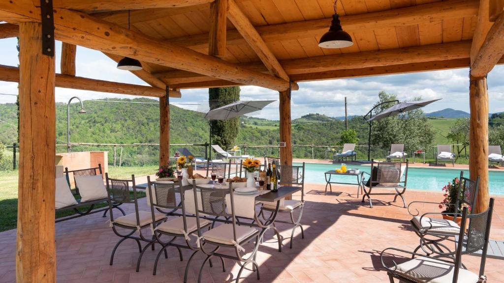 un patio avec une table et des chaises et une piscine dans l'établissement Podere Capanna - Il Tuo Rifugio di Relax nella Campagna Toscana, à Montecatini Val di Cecina