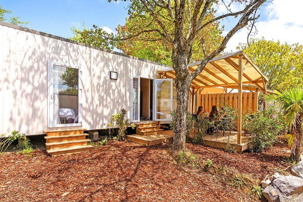 une petite maison blanche avec un arbre en face dans l'établissement Camping Domaine Berrua - Maeva Sélection, à Bidart