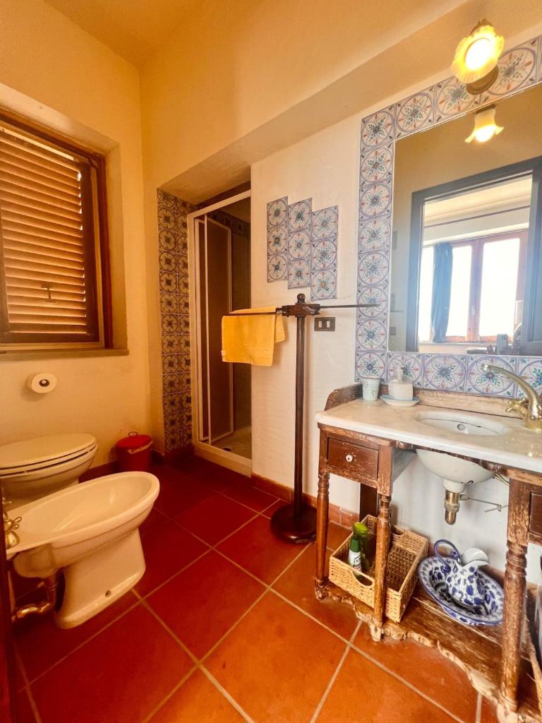 une salle de bain avec toilettes, lavabo et miroir dans l'établissement Villa Cresta, private villa with pool, à Naso