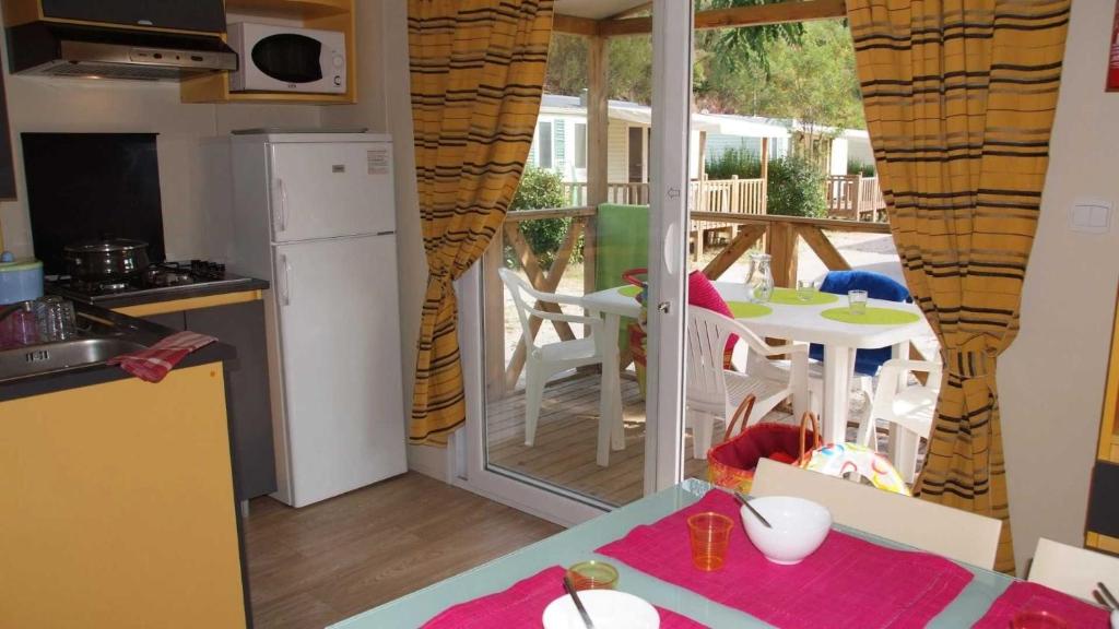Il comprend une cuisine avec un balcon doté d'une table et de chaises. dans l'établissement Camping 4 étoiles - Parc aquatique - eec0ef, à Agay