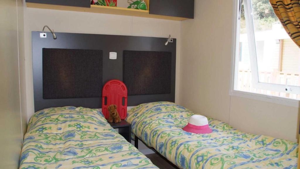 - une chambre avec 2 lits jumeaux avec un chapeau dans l'établissement Camping 4 étoiles - Parc aquatique - eec0ef, à Agay