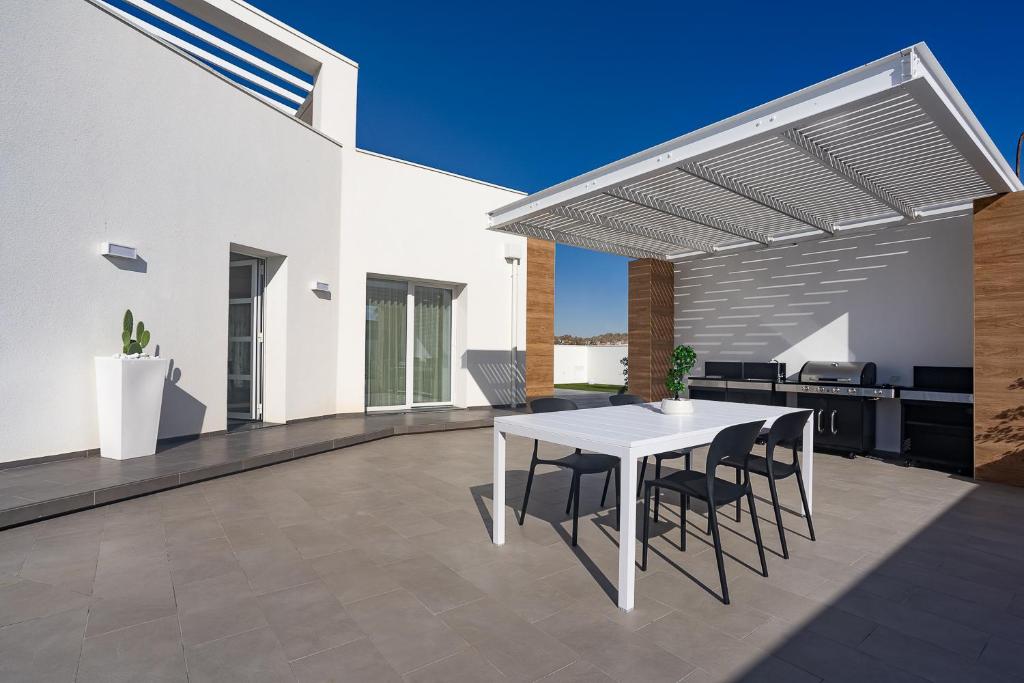une table blanche et des chaises sur une terrasse dans l'établissement Villa Iside, à Marina di Ragusa