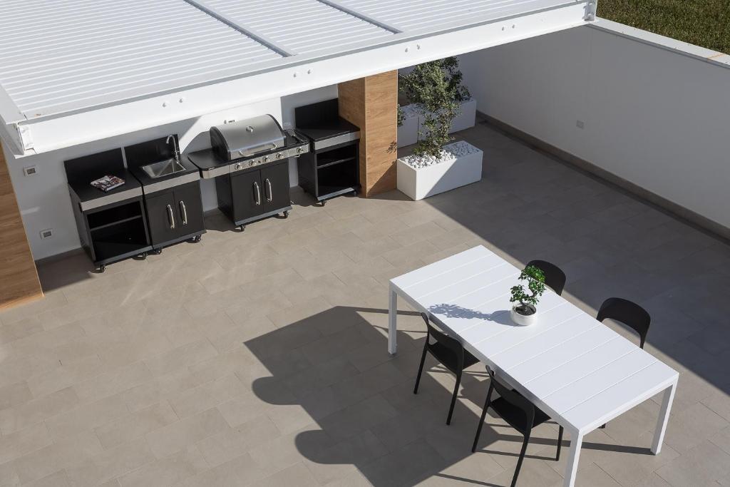 Elle offre une vue sur la terrasse dotée d'une table et de chaises blanches. dans l'établissement Villa Iside, à Marina di Ragusa