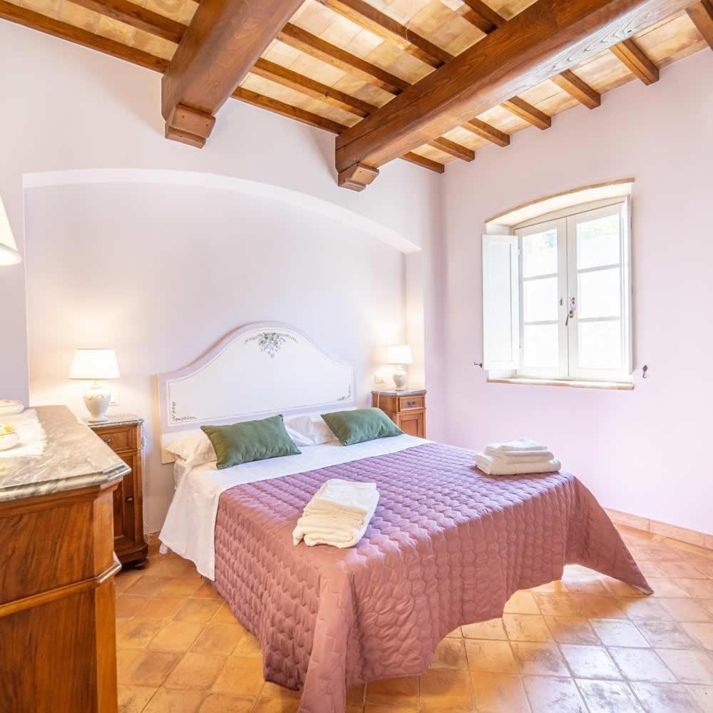 une chambre avec un grand lit et une fenêtre dans l'établissement villa il sasseto, à Castel Viscardo