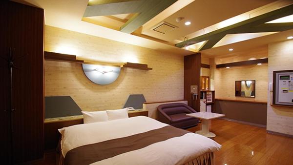 une chambre d'hôtel avec un lit et une chaise dans l'établissement Hotel Dolphin, à Ishinomaki