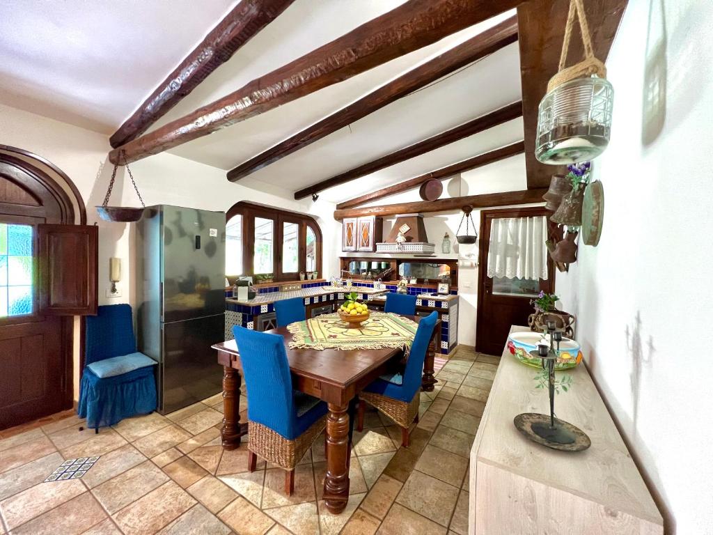 une cuisine avec une table en bois et des chaises bleues dans l'établissement Villa Ólea Resort, à Carini