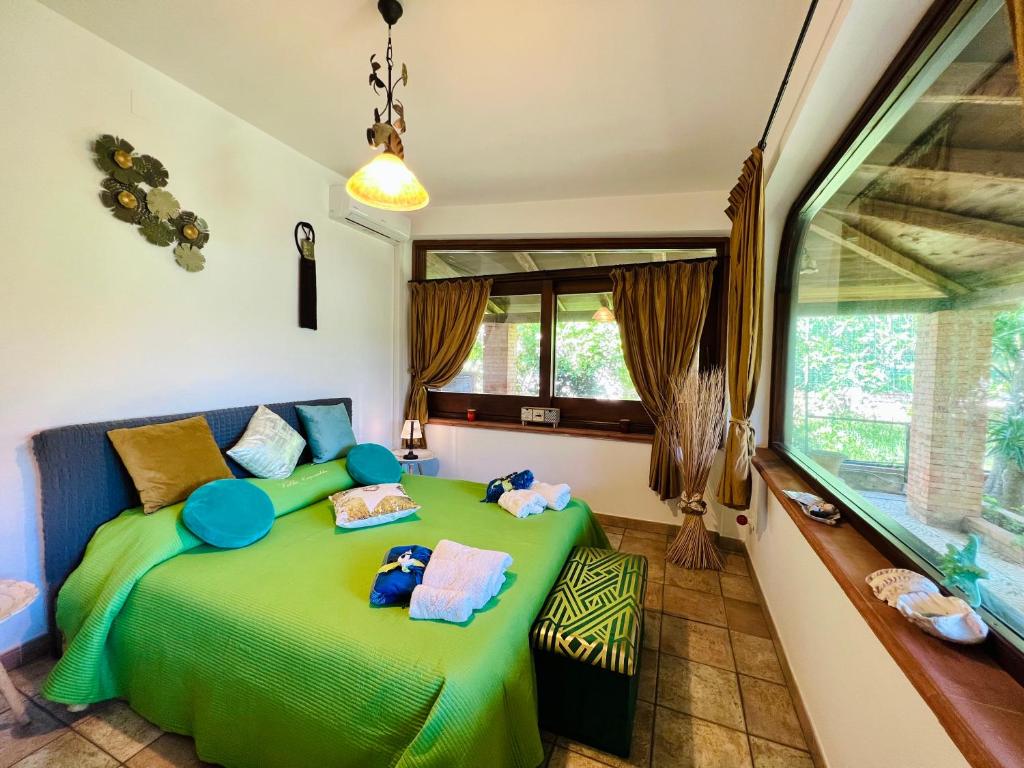 une chambre avec un lit vert et une fenêtre dans l'établissement Villa Ólea Resort, à Carini