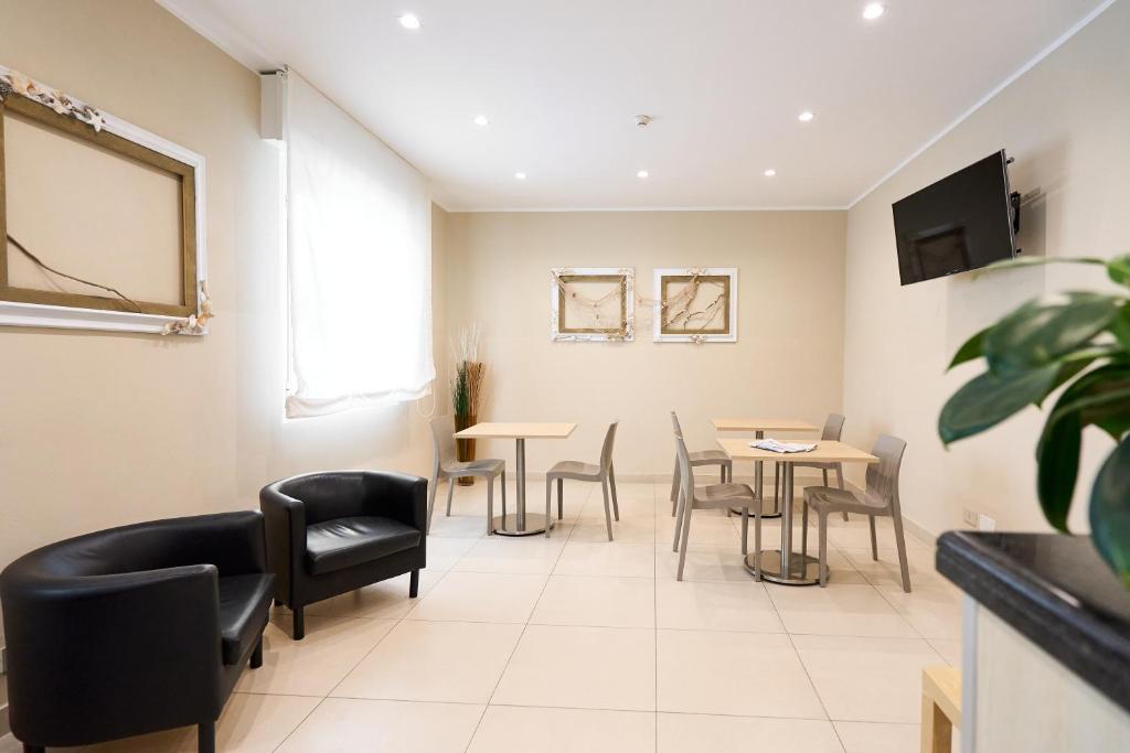une salle d'attente avec des tables et des chaises et une télévision dans l'établissement Hotel Villa Perazzini, à Rimini