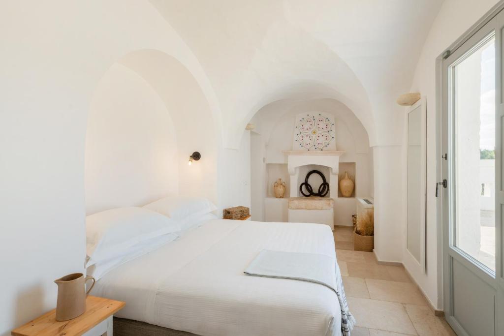 une chambre blanche avec un lit et une fenêtre dans l'établissement Masseria Borgopietra, à Ostuni