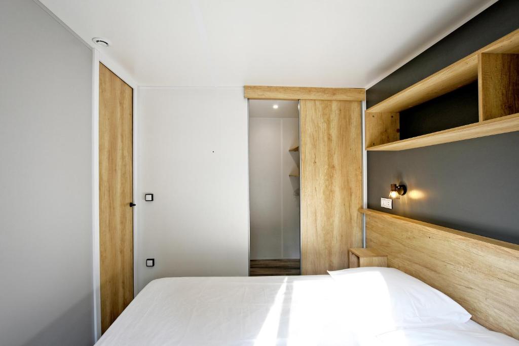 - une chambre avec un lit blanc et des étagères en bois dans l'établissement Camping Les Castors, à Calvi