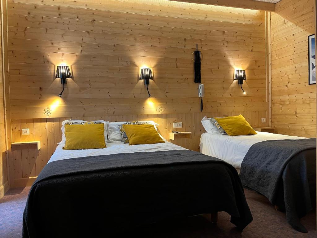 - 2 lits dans une chambre dotée de murs en bois et de lumières dans l'établissement Hotel le Sacca, nouvelle équipe, à Cauterets