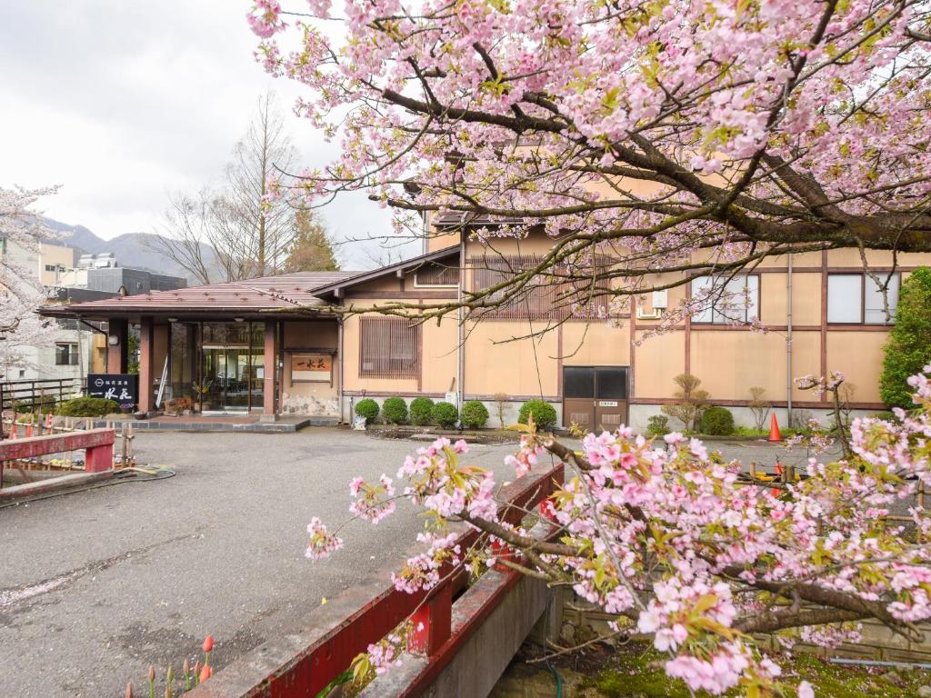 un arbre aux fleurs roses devant un bâtiment dans l'établissement 一水荘, à Gosen