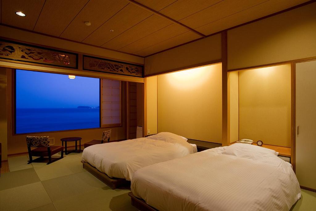 deux lits dans une chambre avec une grande fenêtre dans l'établissement Hanagoyomi, à Sumoto 37 autres photos