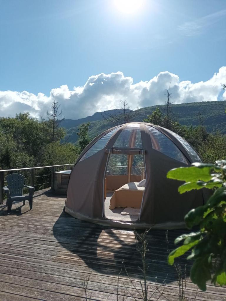 une tente installée au-dessus d'une terrasse en bois dans l'établissement Bulle en bois sous les étoiles, à Champfromier
