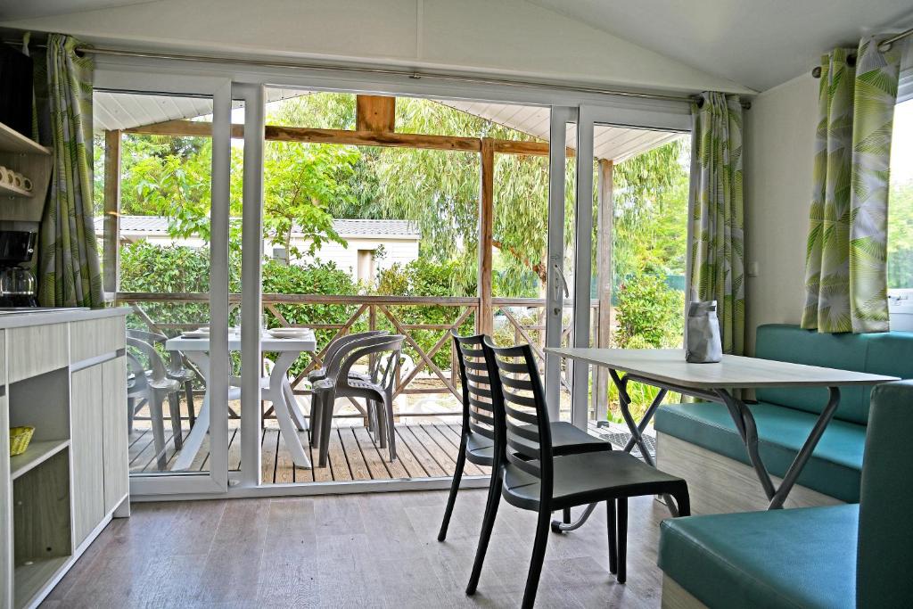 un salon avec une table et des chaises et un balcon dans l'établissement Camping Les Castors, à Calvi