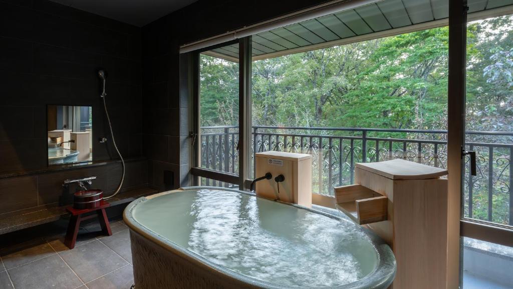 une baignoire dans une pièce avec une grande fenêtre dans l'établissement Nasu-Onsen Shinshun no Kago Hewitt Resort, à Nasu