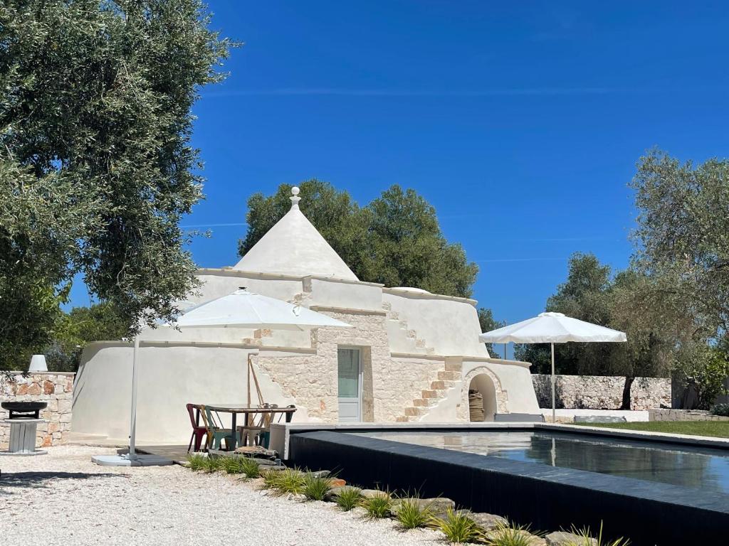 une villa avec une piscine, une table et un parasol dans l'établissement Luxury Trullo Ostuni, à Ostuni