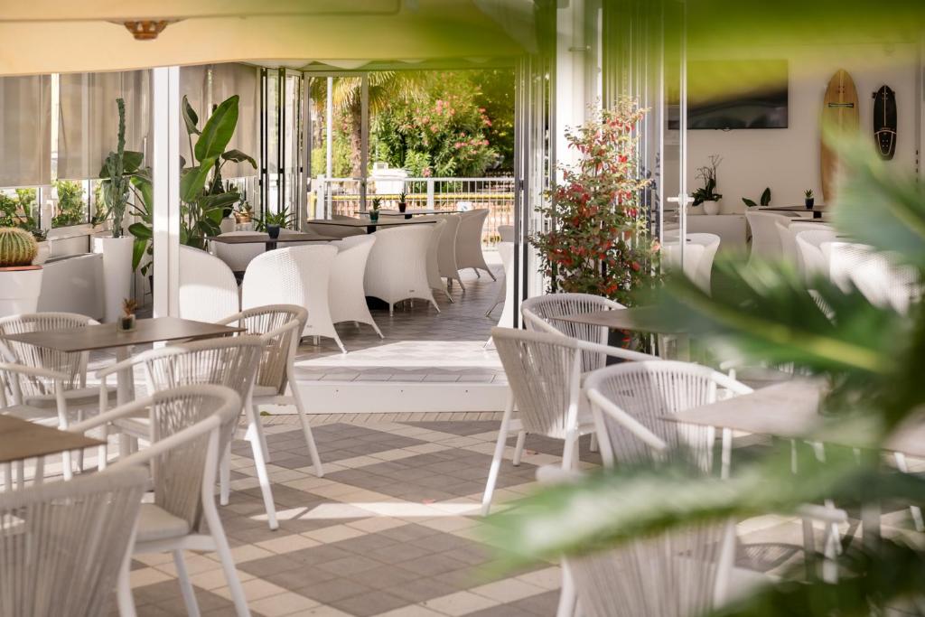 - un restaurant avec des tables et des chaises blanches sur la terrasse dans l'établissement All'Orologio - Boutique Hotel, à Caorle
