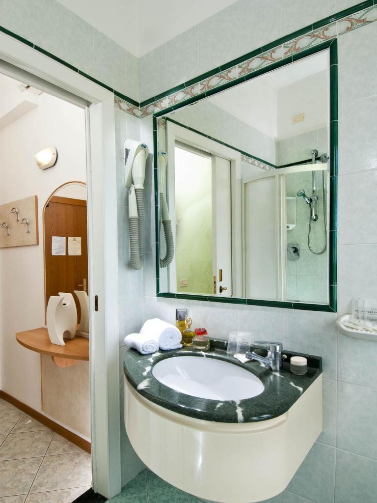 une salle de bain avec un lavabo et un miroir dans l'établissement Hotel Gloria, à Gabicce Mare