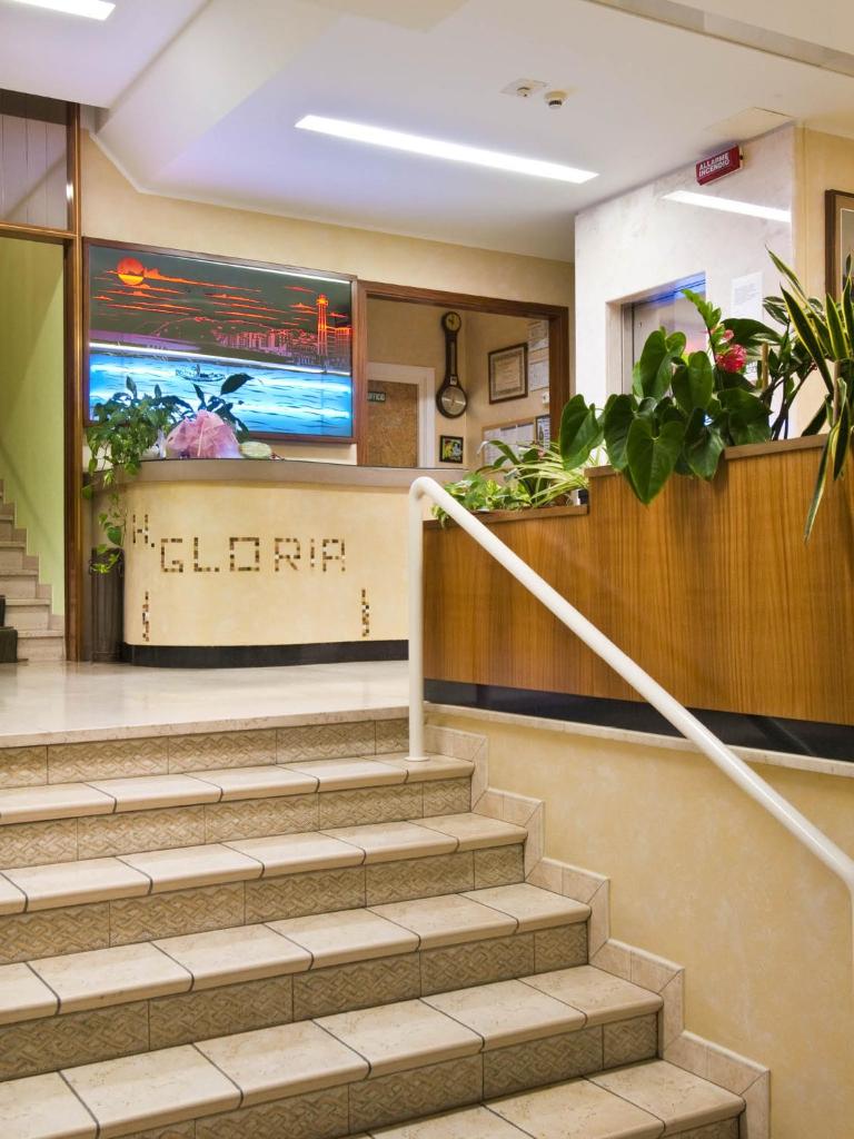 un hall d'entrée avec des escaliers et des plantes dans un immeuble dans l'établissement Hotel Gloria, à Gabicce Mare