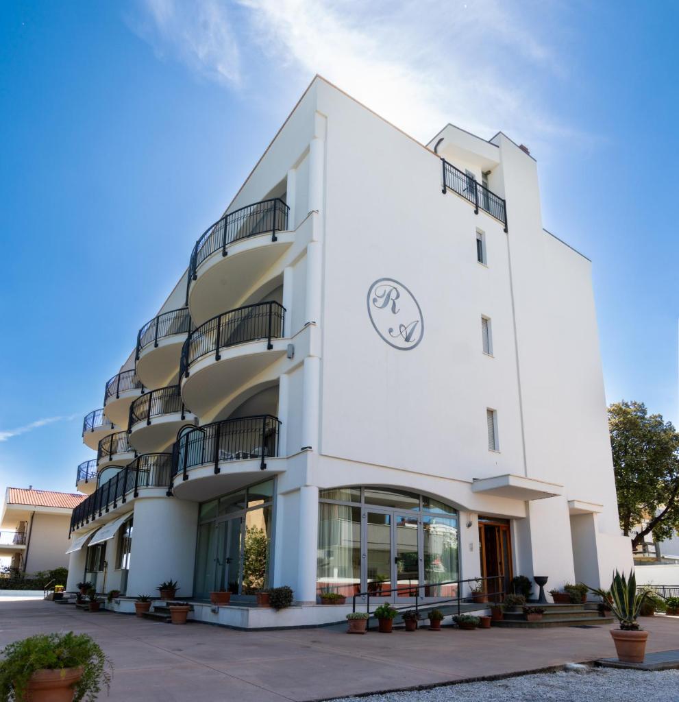 un bâtiment blanc avec une horloge dessus dans l'établissement Altamira Residence, à Roseto degli Abruzzi
