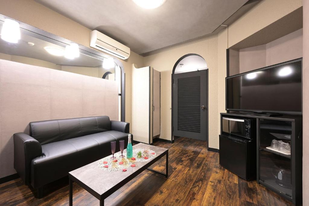 un salon avec un canapé, une télévision et une table dans l'établissement Hotel NEO, à Honjo