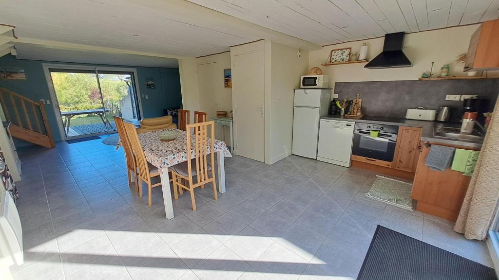 une cuisine avec une table et des chaises dans une pièce dans l'établissement Gites O Ptit Bonheur - Vendée - 2 Maisons de 85 m2 chacune avec piscine extérieure chauffée & couverte, à Saint-Christophe-du-Ligneron