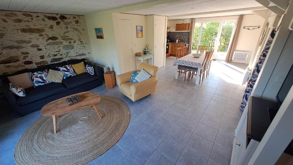 un salon avec un canapé bleu et une table dans l'établissement Gites O Ptit Bonheur - Vendée - 2 Maisons de 85 m2 chacune avec piscine extérieure chauffée & couverte, à Saint-Christophe-du-Ligneron