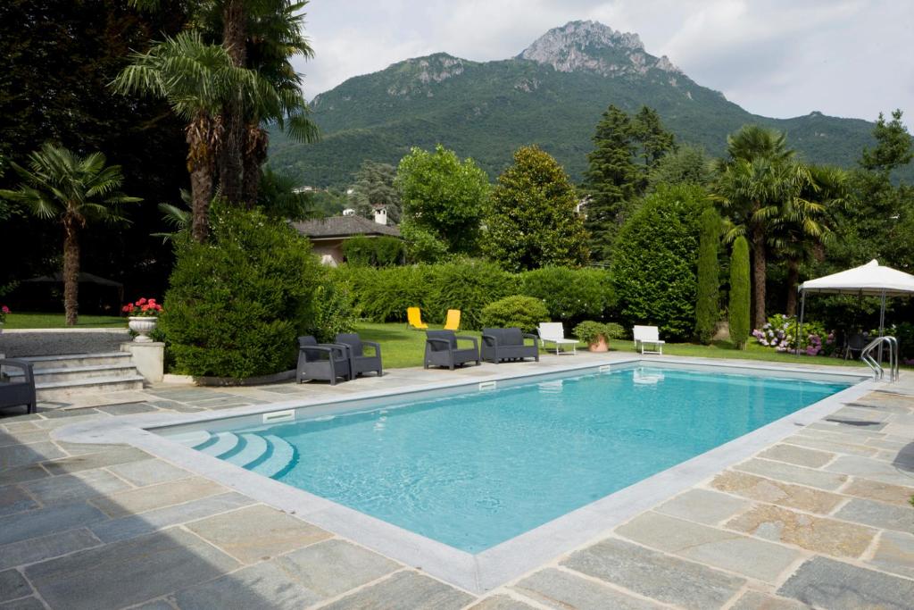 une piscine avec des chaises et des montagnes en arrière-plan dans l'établissement Villa Confalonieri, à Mandello del Lario