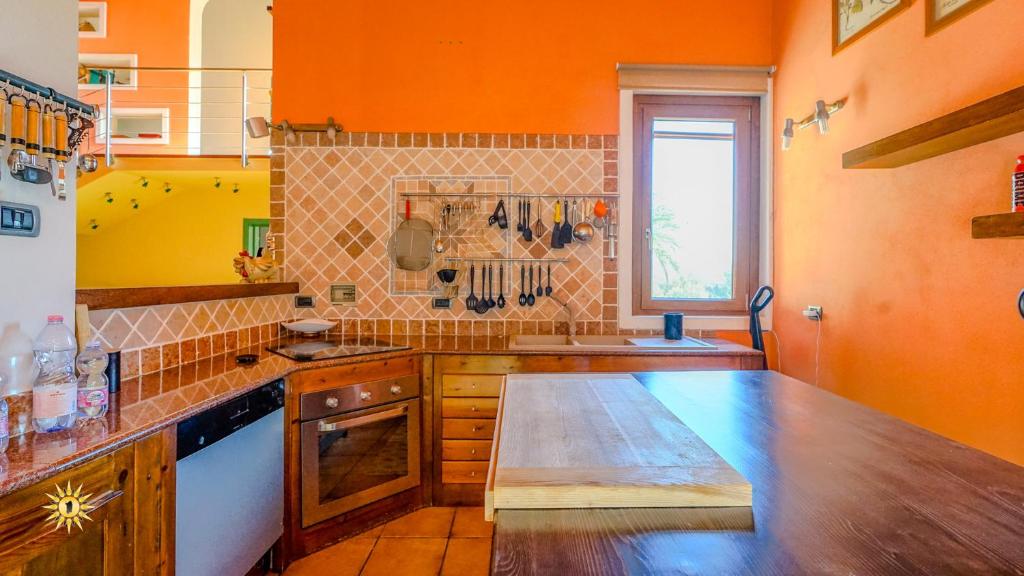 - une cuisine avec des murs orange et un comptoir en bois dans l'établissement Villa Gambula - Relax and Pool, à Perdaxius