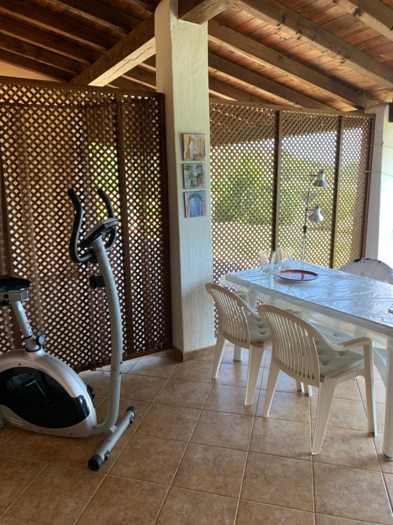 Cette chambre comprend une table, un vélo d'appartement, une table et des chaises. dans l'établissement Villa EMPATJA, à Tertenìa