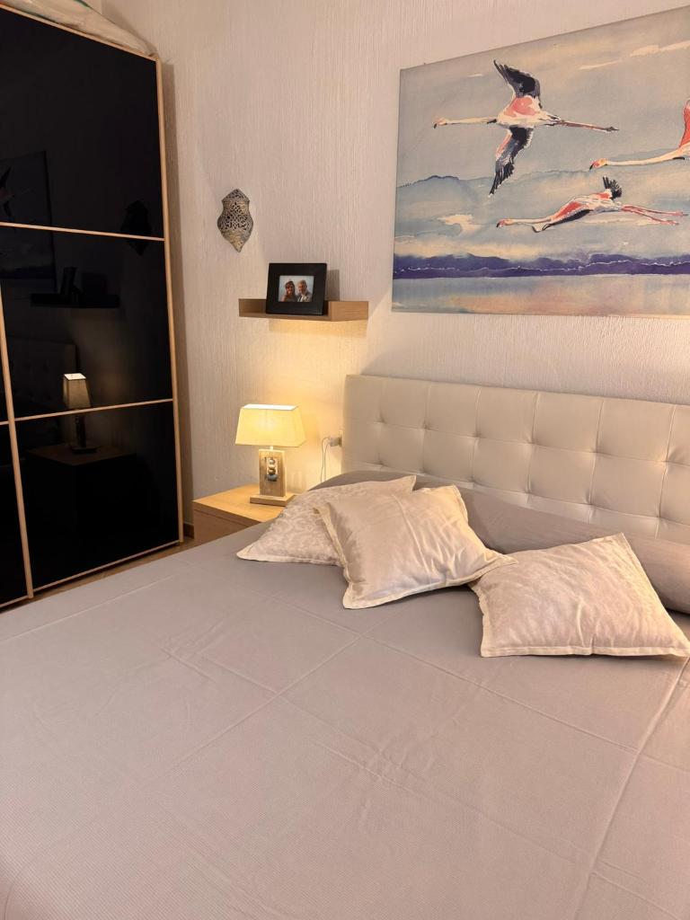 une chambre avec un lit blanc avec un tableau sur le mur dans l'établissement Villa EMPATJA, à Tertenìa