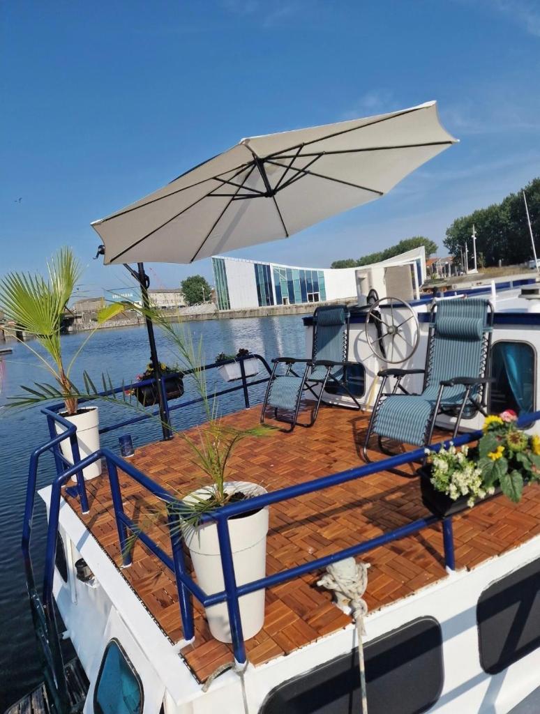- une terrasse avec des chaises et un parasol sur un bateau dans l'établissement Calaidonia boat house, à Calais