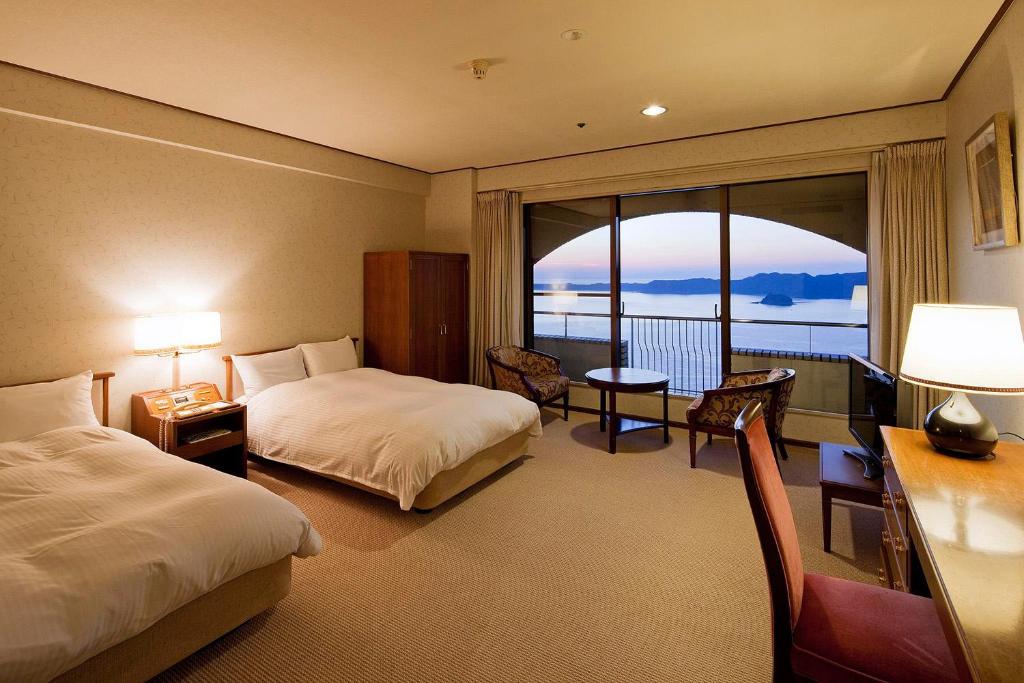 une chambre d'hôtel avec deux lits et un balcon dans l'établissement Plaza Awajishima, à Minamiawaji