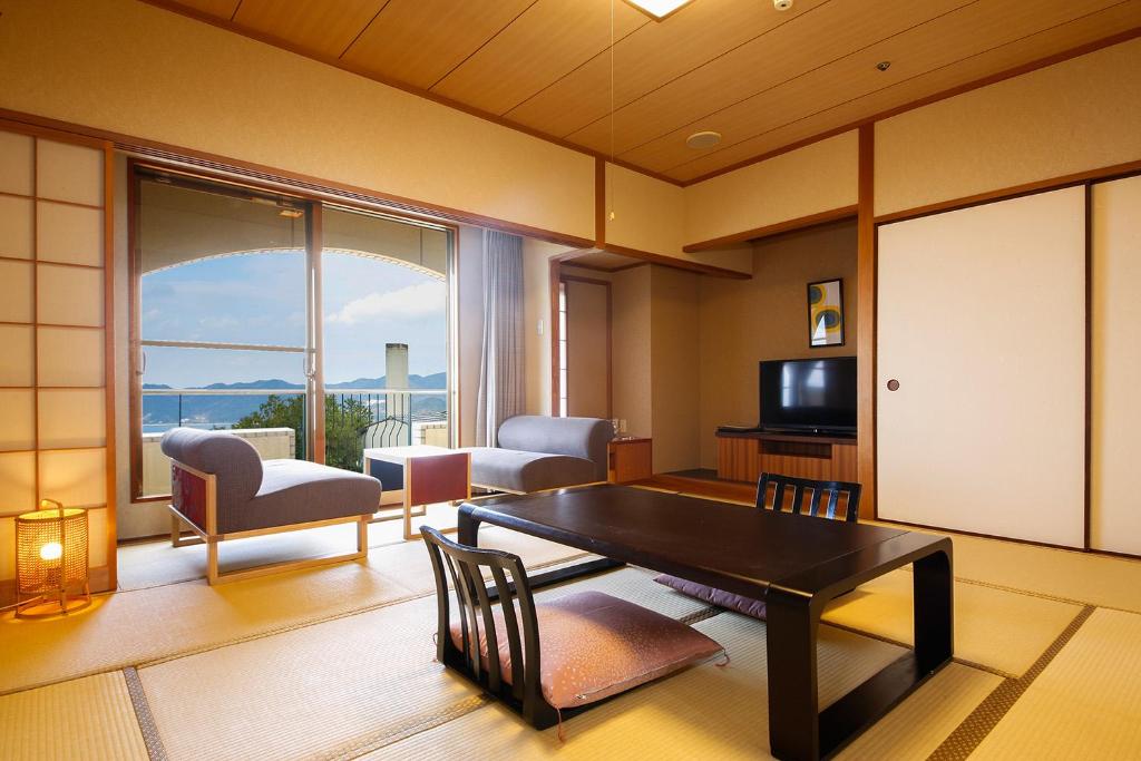 - un salon avec une table, des chaises et une grande fenêtre dans l'établissement Plaza Awajishima, à Minamiawaji