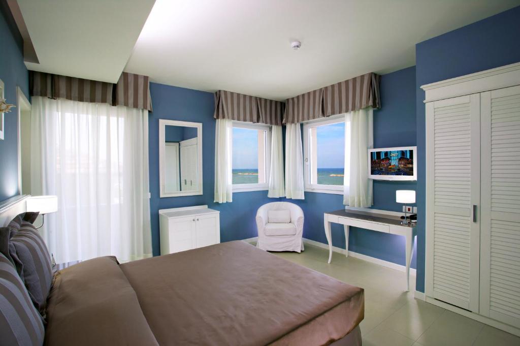 - une chambre avec des murs bleus et un lit avec un bureau dans l'établissement Hotel Nettuno, à Cesenatico