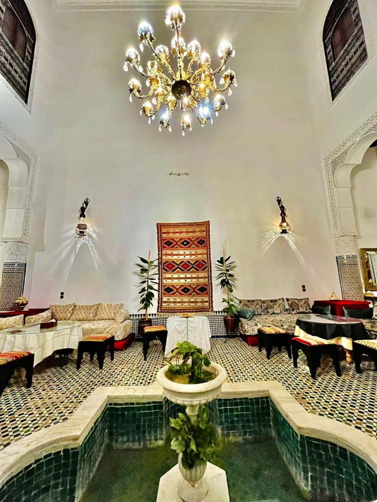 un grand hall avec un lustre et une piscine dans l'établissement Riad Lalla Zoubida, à Fès