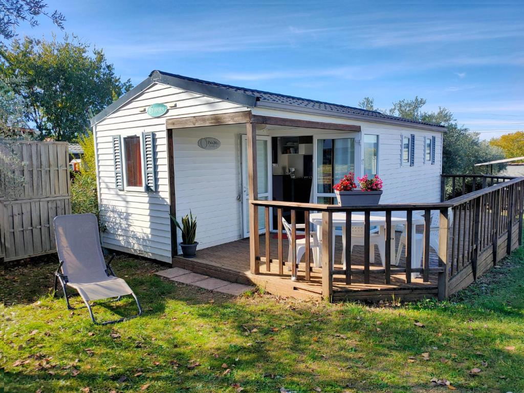 un petit hangar blanc avec une terrasse et une chaise dans l'établissement Camping les Oliviers, à Oraison